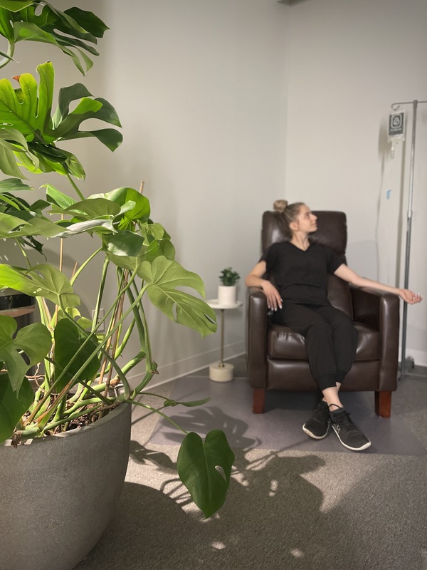 woman recieving IV treatment in cura IV lounge with monstera plant in the forefront