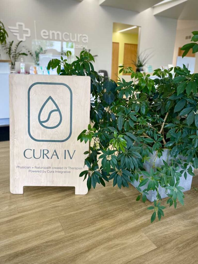 wooden sandwich board with cura iv logo beside big plant in front of reception desk